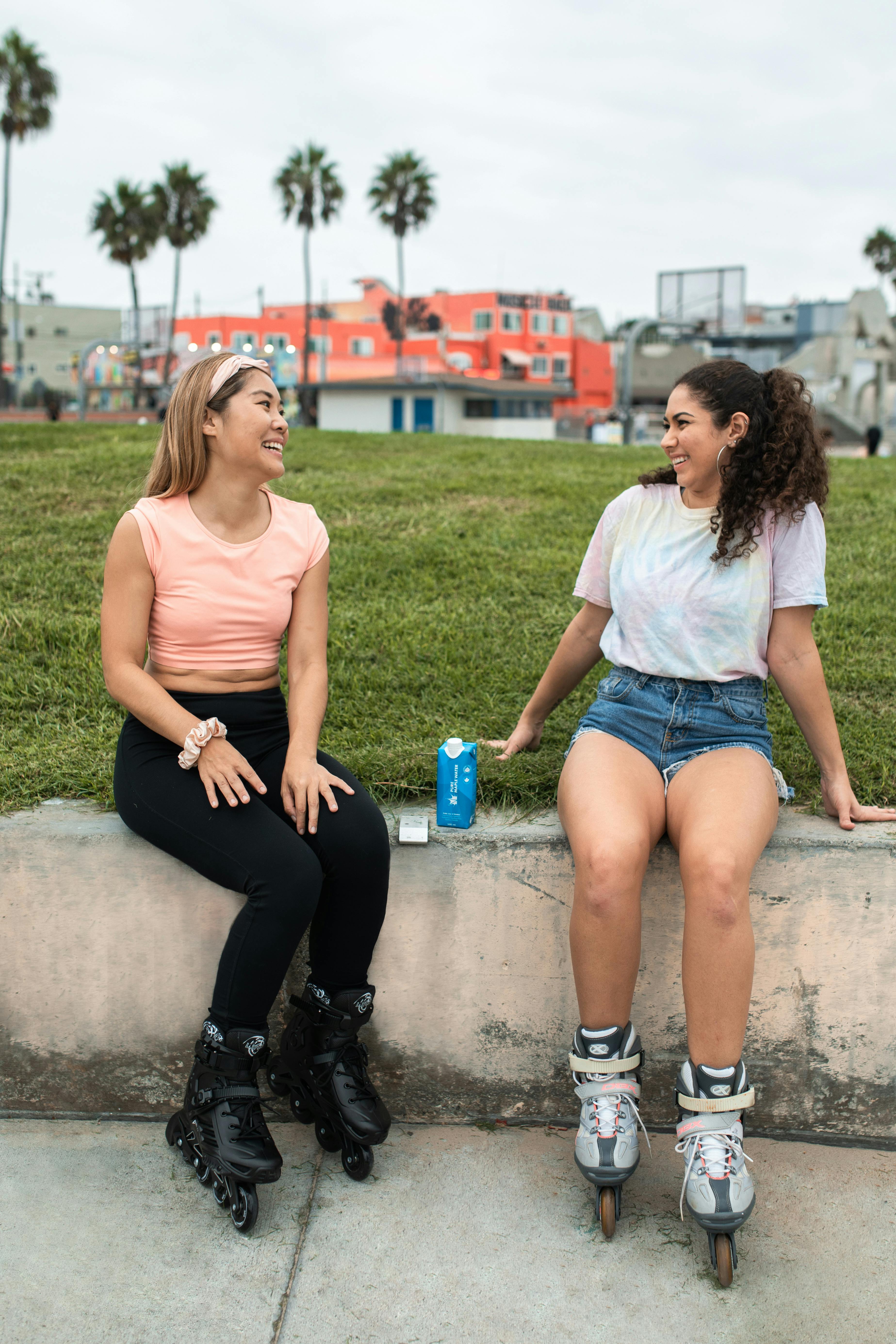 women sitting on concrete wearing rollerblades