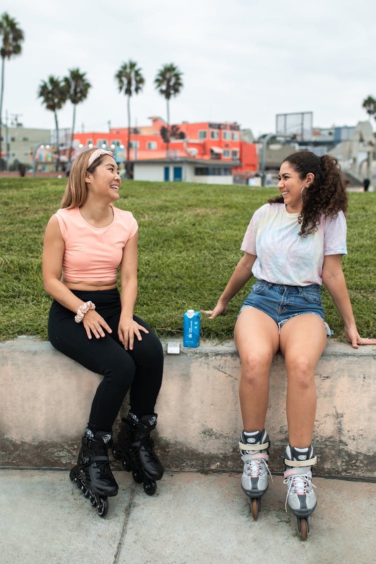 Women Sitting On Concrete Wearing Rollerblades