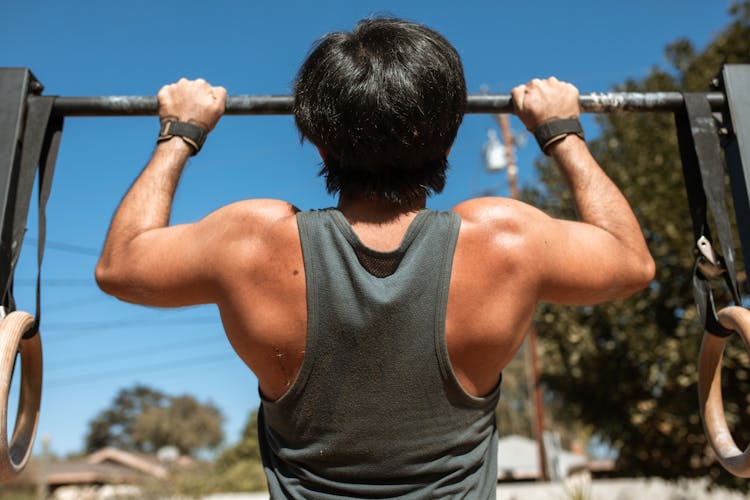 Man In Gray Tank Top Doing Pull Ups On Black Pull Up Bar