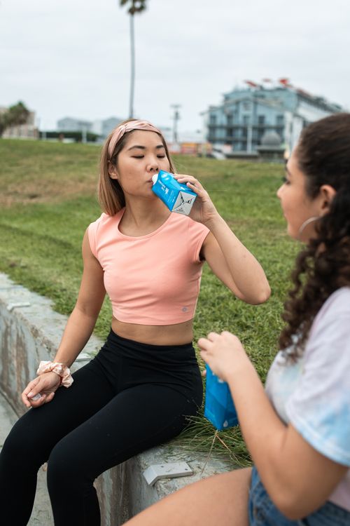 Free Two women enjoying drinks outdoors in a casual setting, showcasing a lifestyle moment. Stock Photo