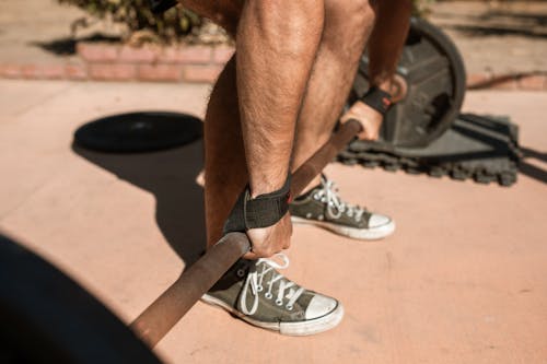 Uomo In Scarpe Da Ginnastica Nike In Bianco E Nero Che Si Siede Sulla Barra Di Metallo Nera