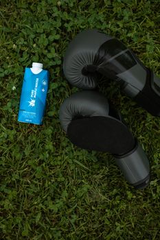 草地上放着拳击手套和纯净的枫水纸箱，象征着水合作用与健身
