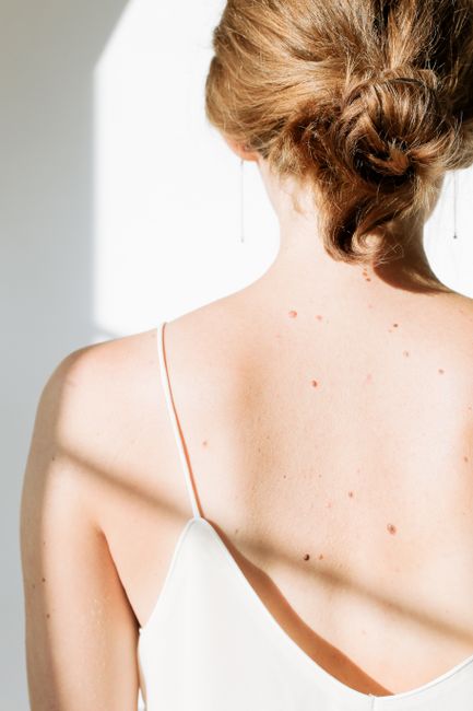 Back view of a woman in a white spaghetti strap dress, showcasing elegance and simplicity.