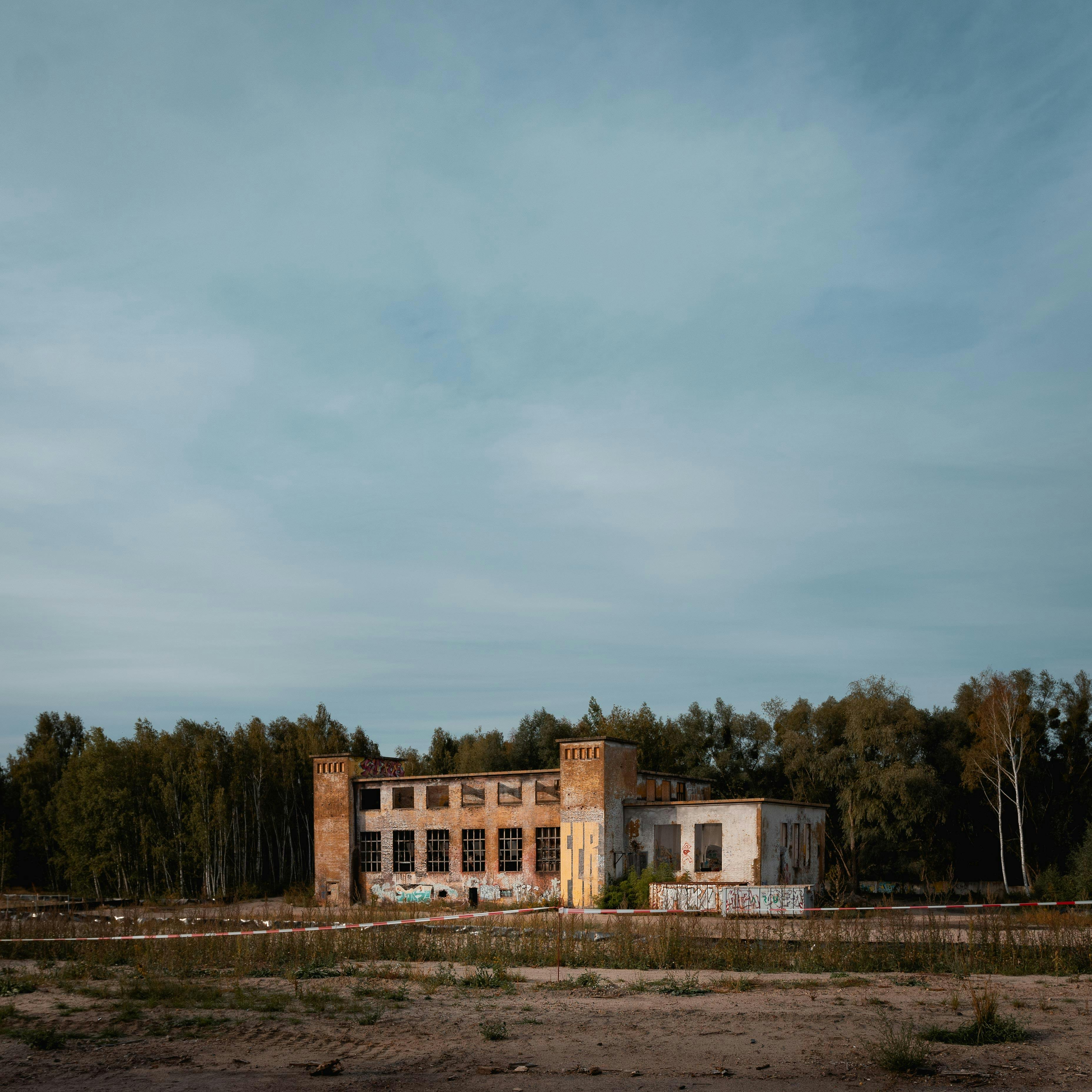 Mysterious abandoned building in Potsdam, Germany, surrounded by trees under a cloudy sky.