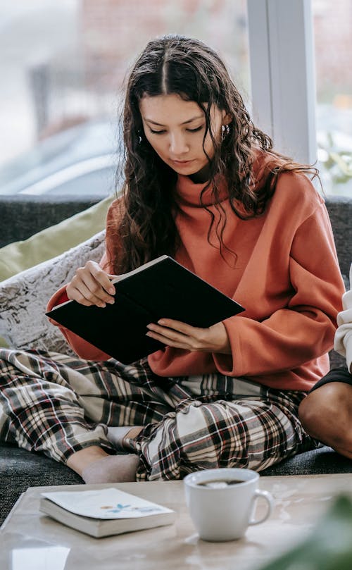 Free Young woman reading book on couch Stock Photo