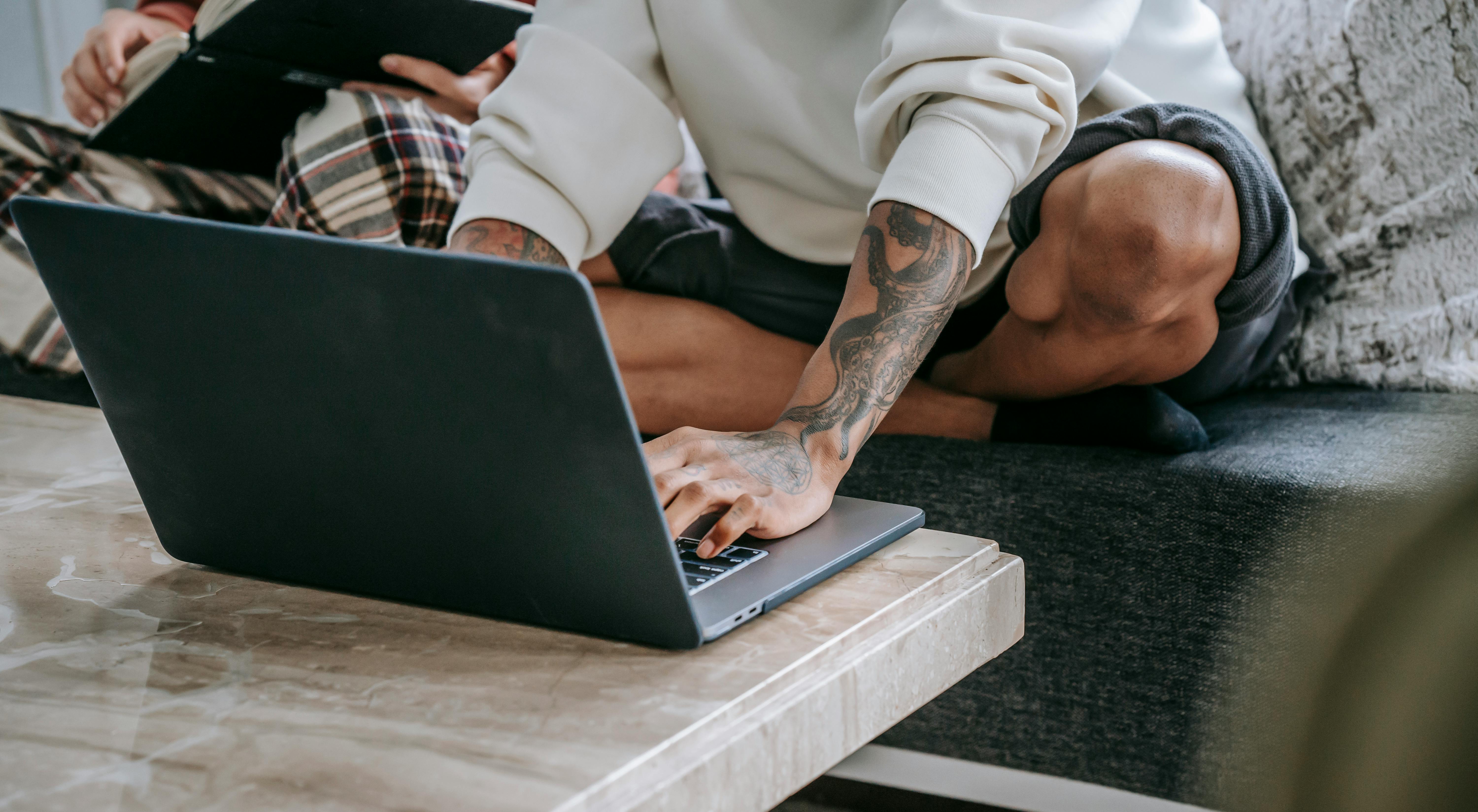 unrecognizable diverse friends typing on laptop in living room