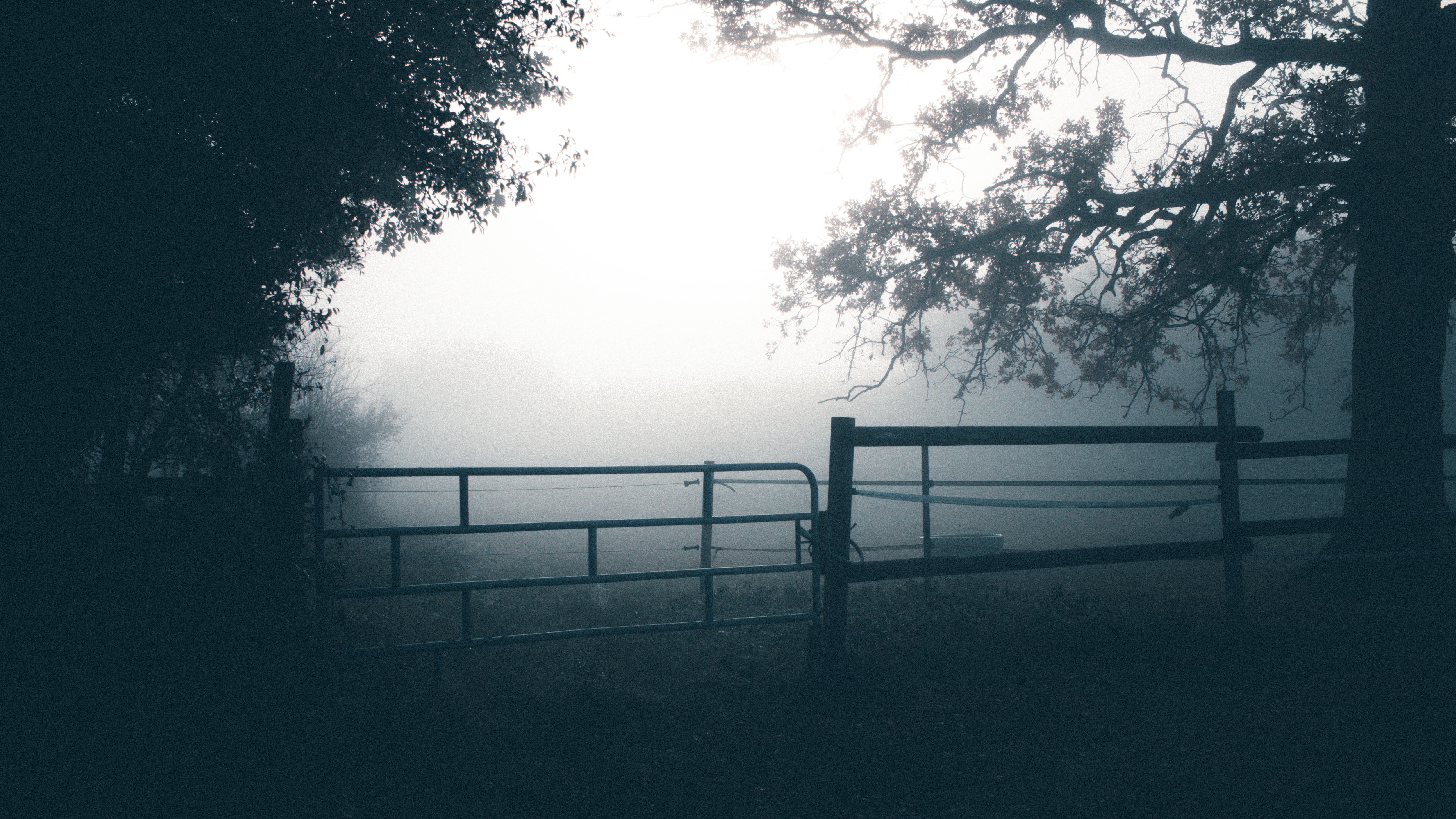 A metal farm gate standing open in a field with a repaired hinge