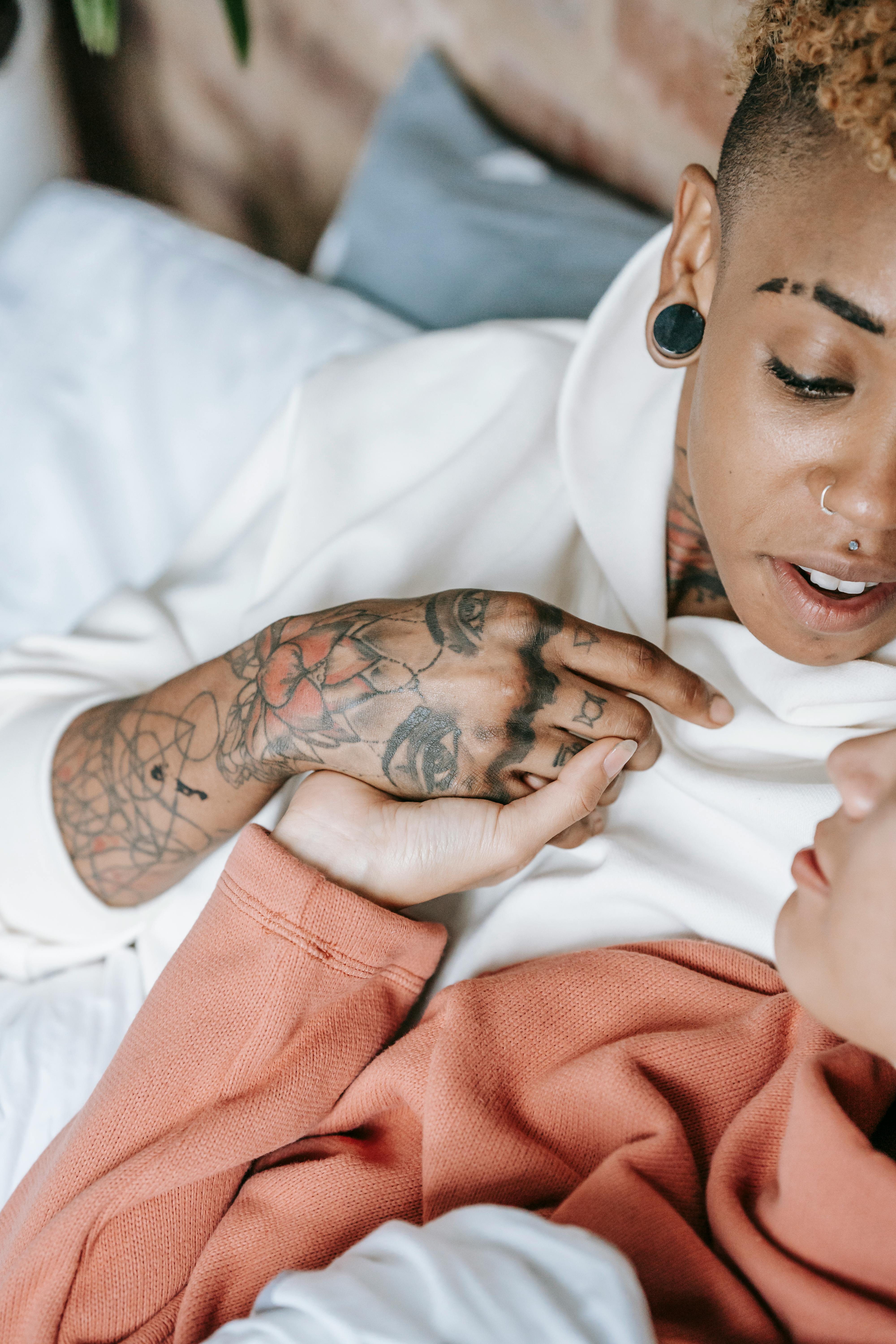 crop diverse couple of lesbian women embracing on bed