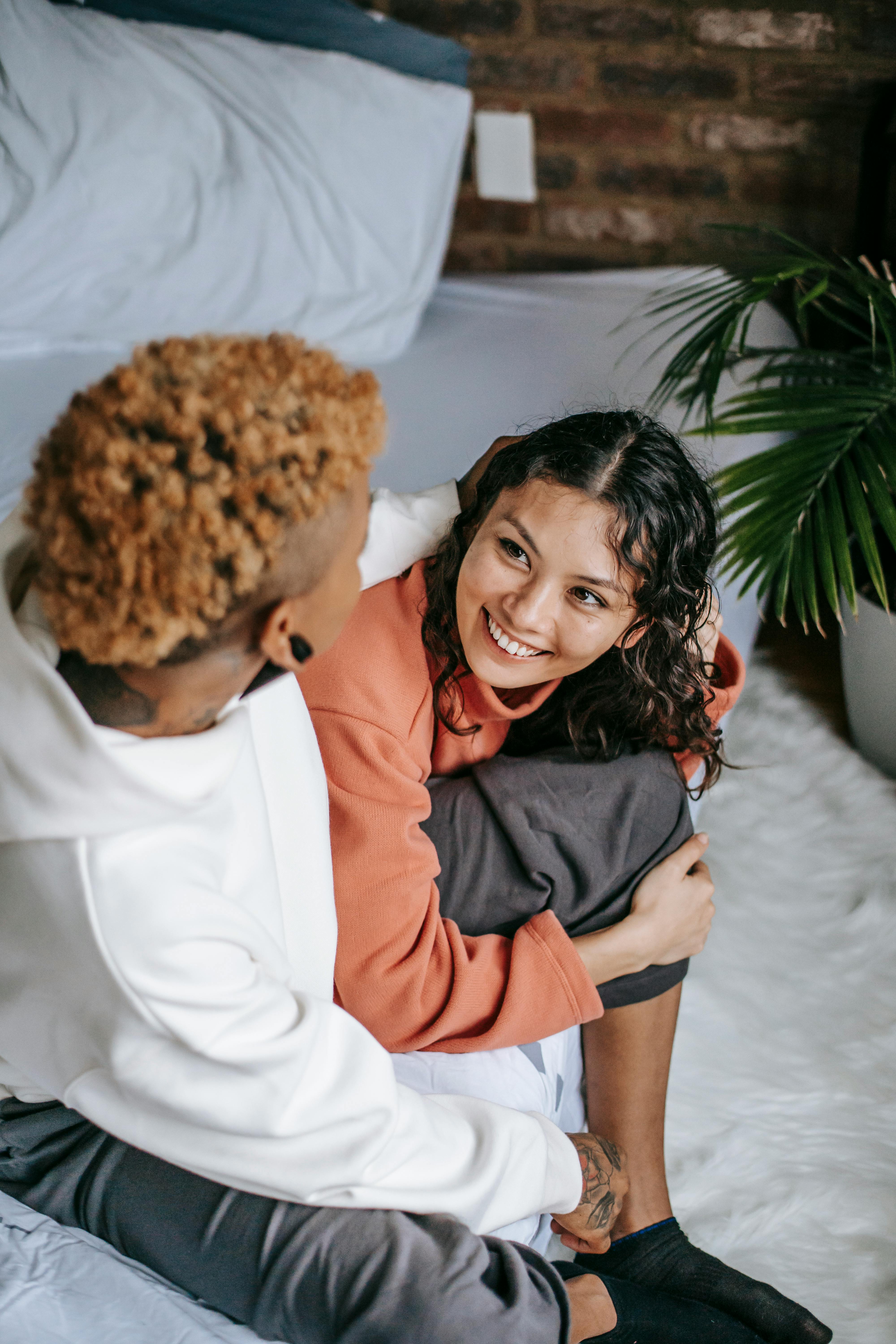 anonymous black woman embracing homosexual ethnic girlfriend on bed