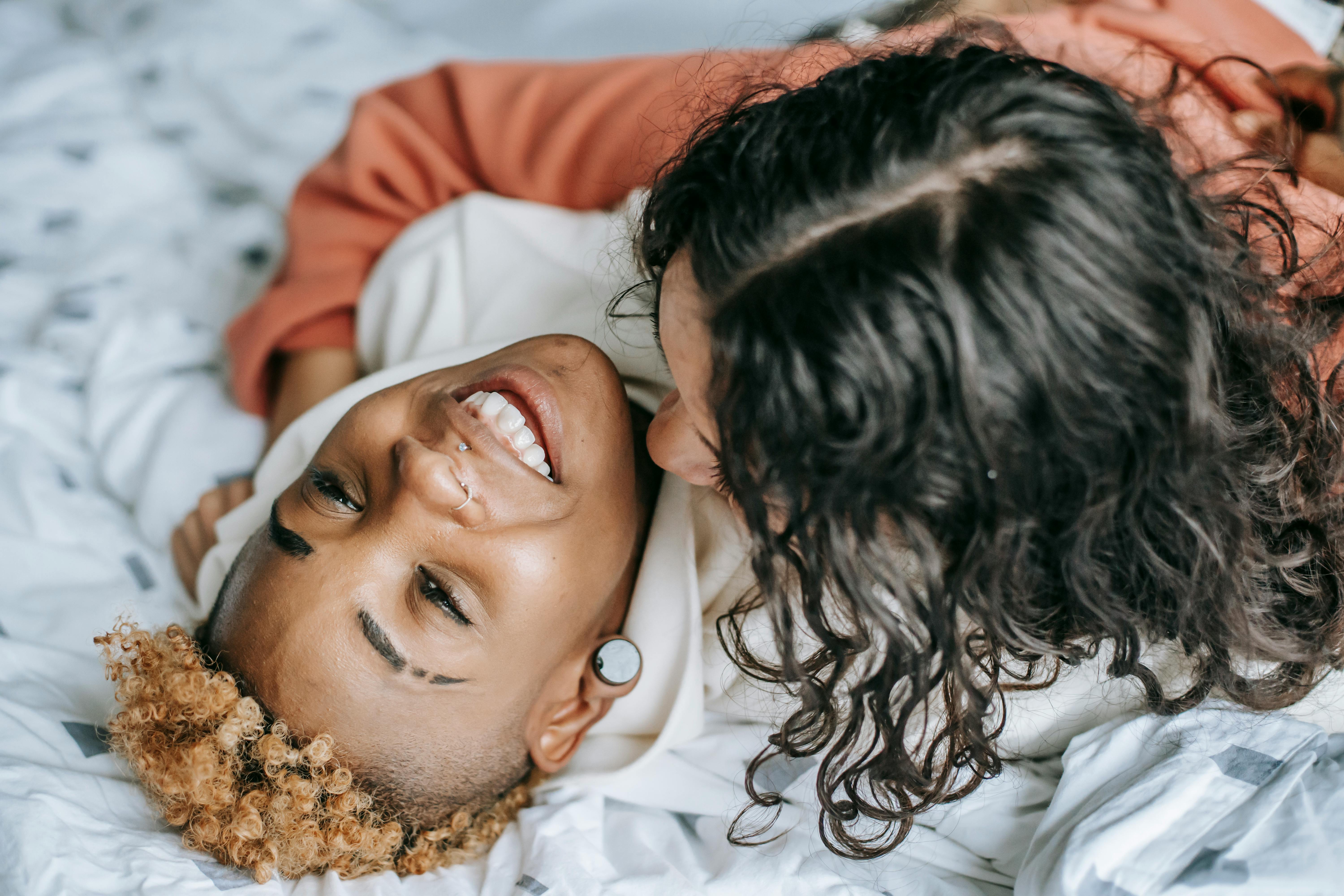 unrecognizable woman embracing happy lesbian girlfriend on bed