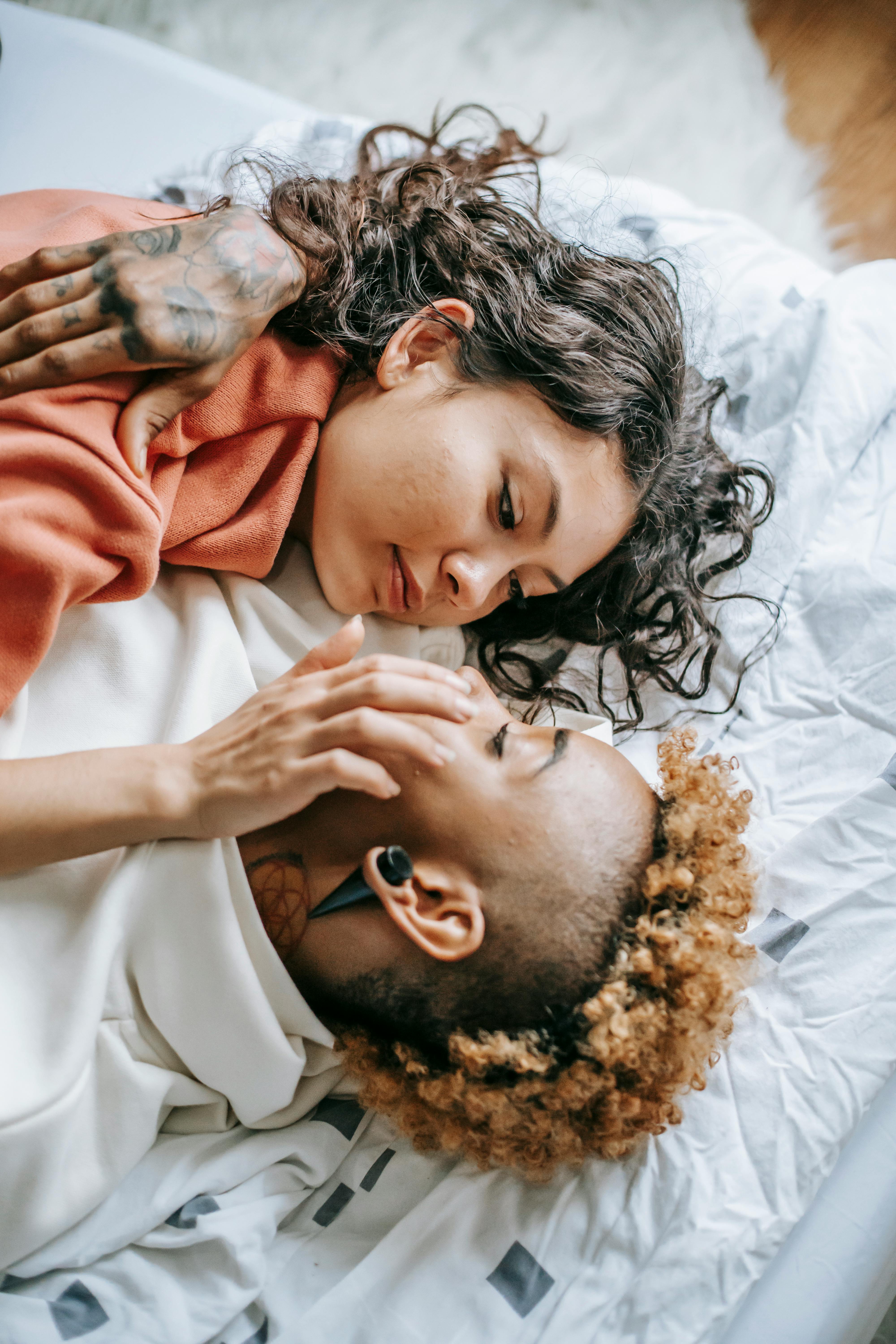 romantic diverse lesbian couple cuddling on cozy bed