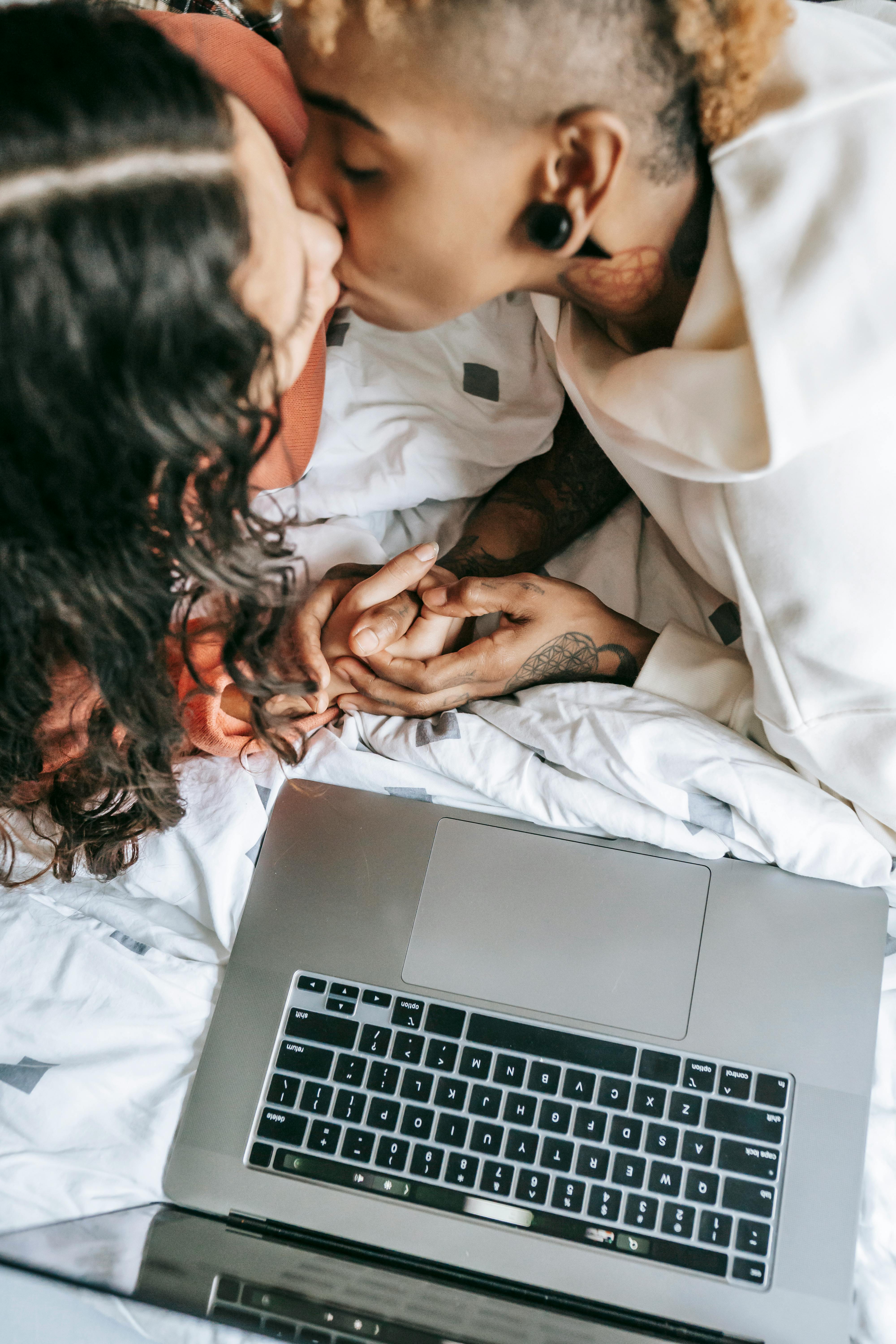 crop loving diverse lesbian couple kissing on bed