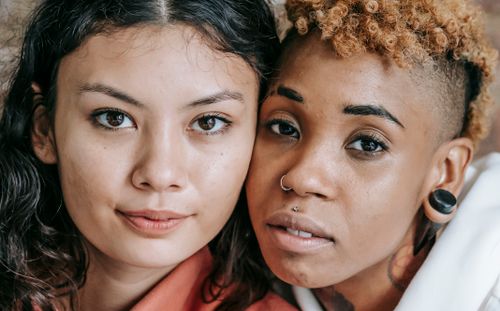 Free Crop serene multiracial girlfriends bonding and holding faces close while looking at camera positively Stock Photo