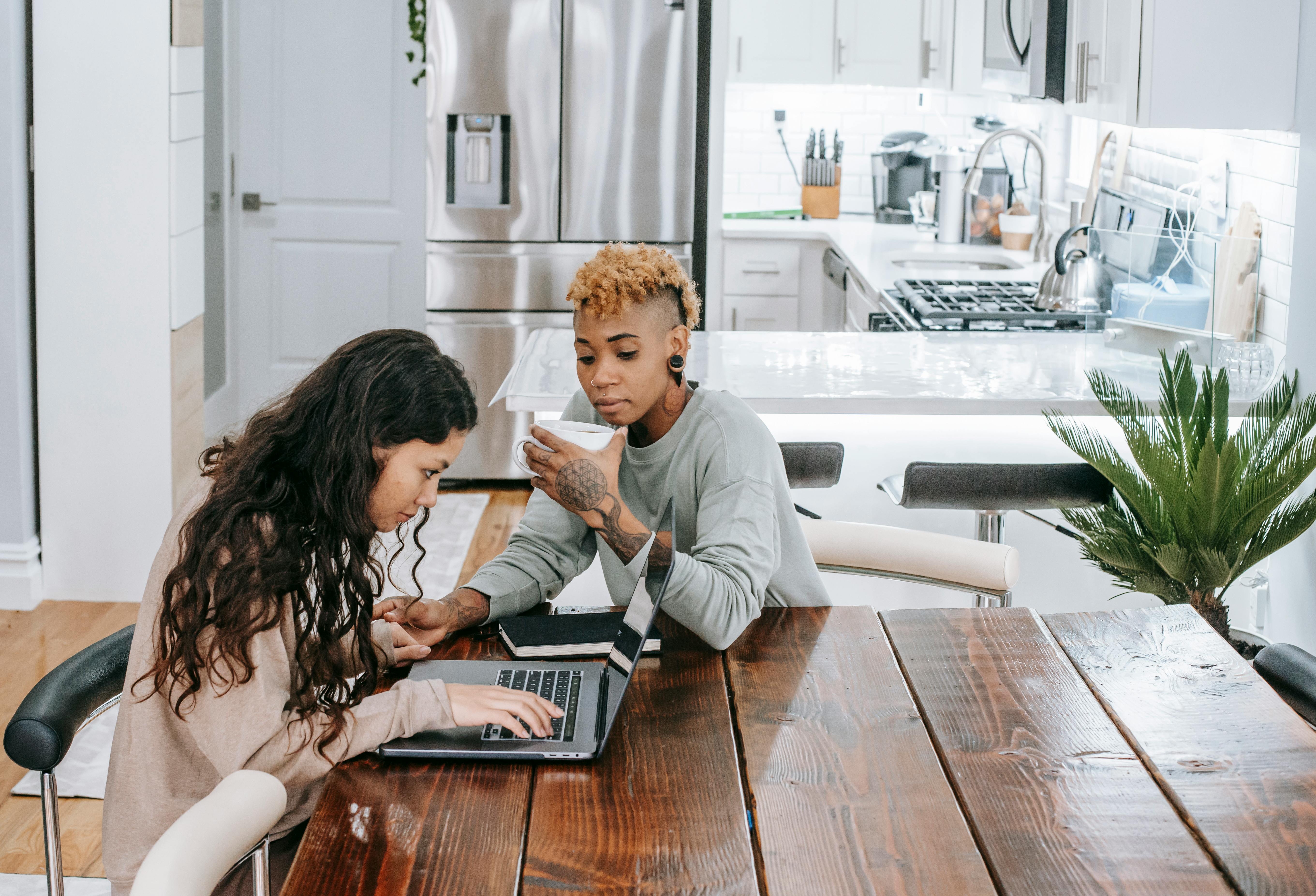 positive multiracial lesbian couple using laptop at table