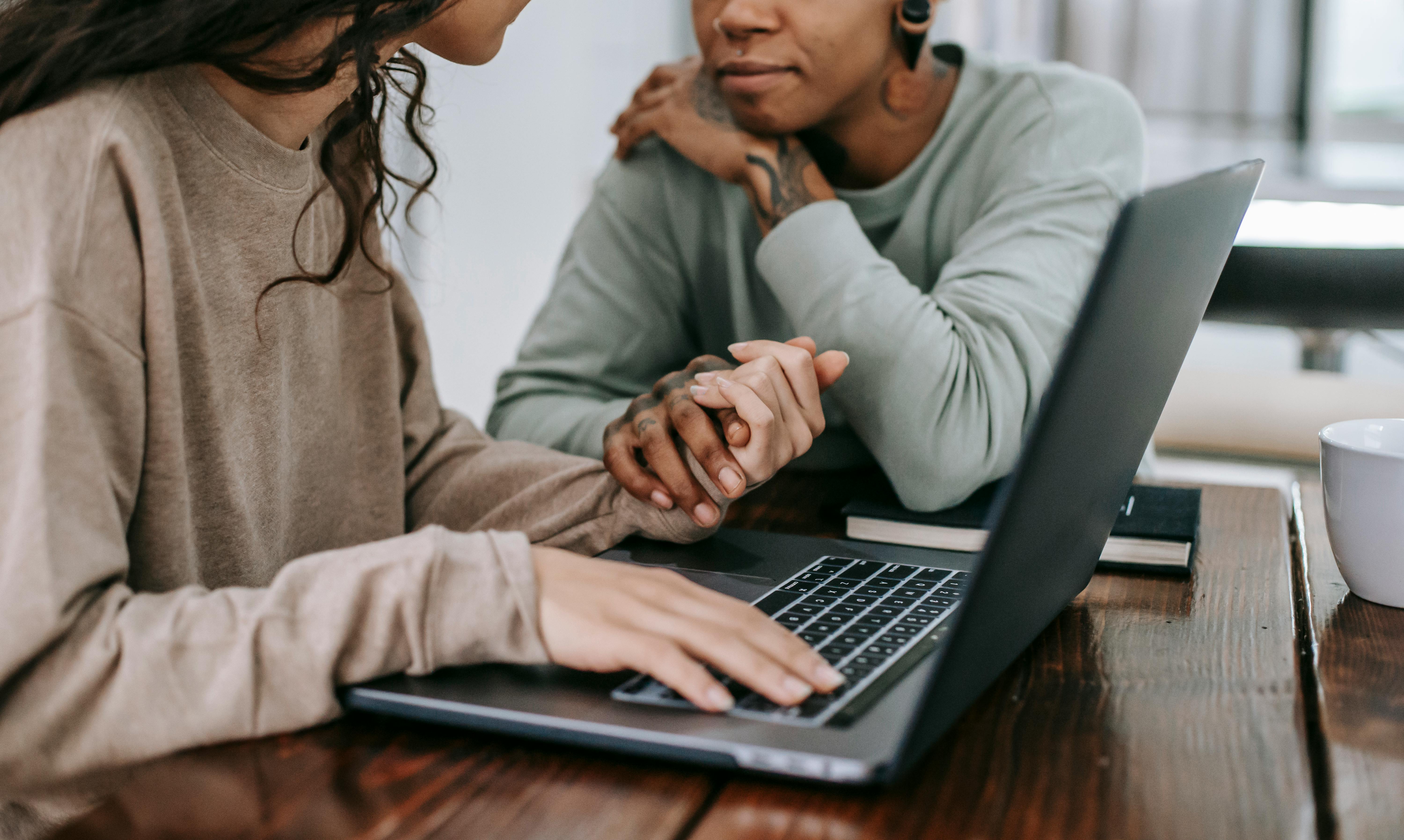 diverse couple with laptop holding hands