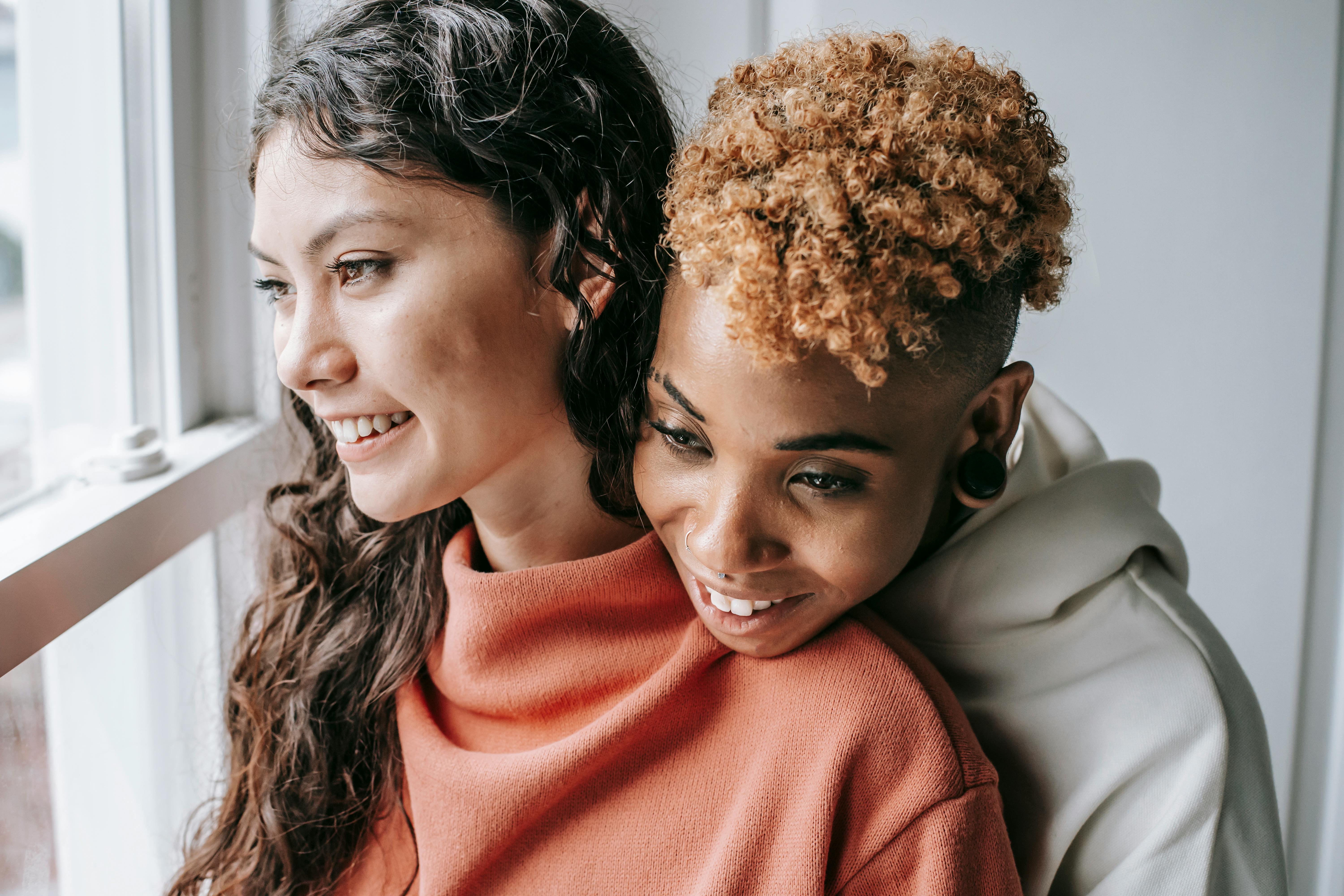 cheerful diverse couple embracing near window