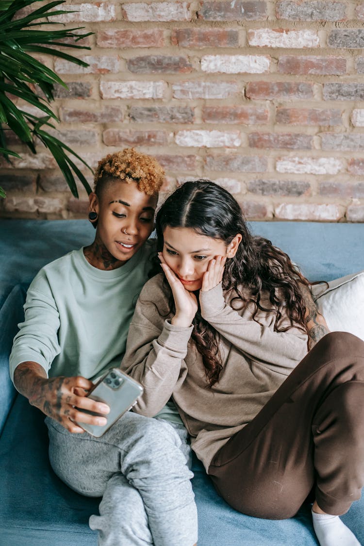 Young Couple With Smartphone Resting On Couch