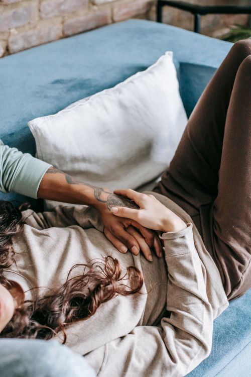 Free Crop faceless couple in casual wear resting together on comfy sofa at home Stock Photo