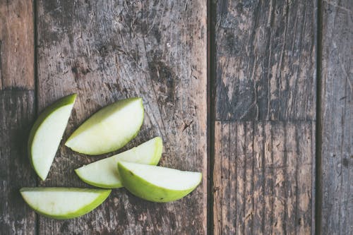 Five Green Sliced Fruit on Brown Wooden Surface