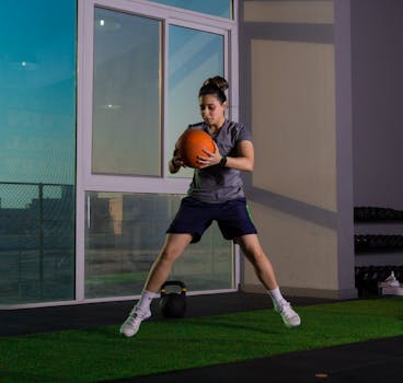 Focused woman working out indoors using a medicine ball for fitness training.