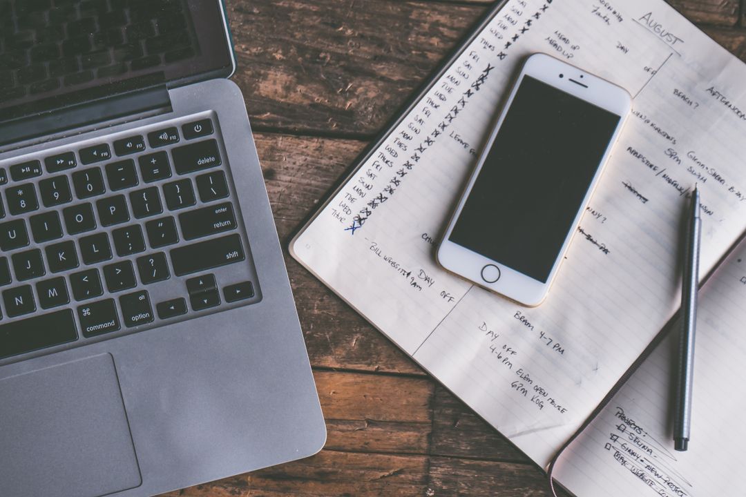 Laptop, smartphone and notebook on a wooden desk
