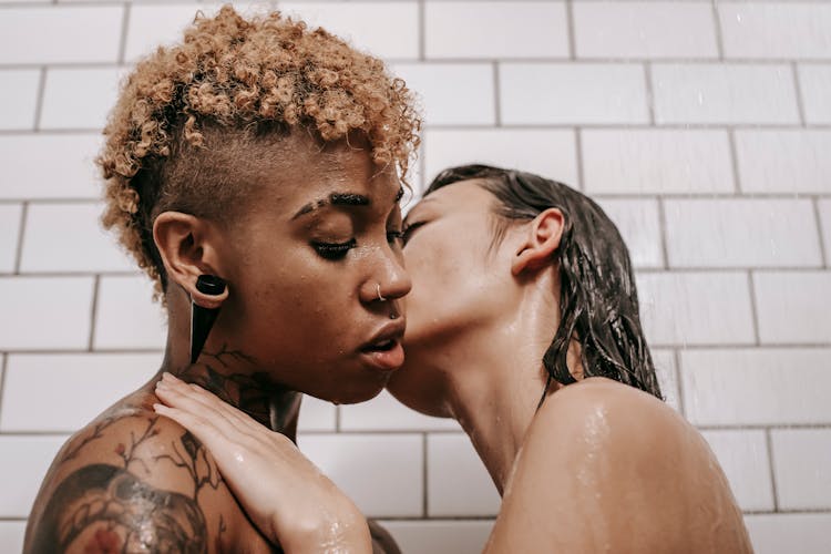 Multiethnic Undressed Female Couple Kissing Under Shower