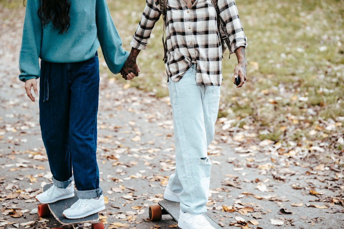 Diverse couple riding longboards in park