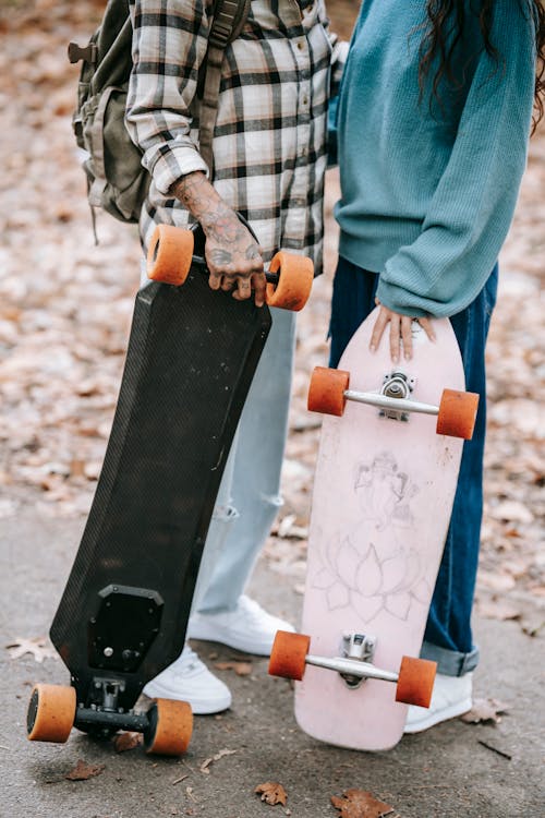 Multiethnic couple with longboards hugging in park