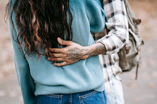 Ethnic tattooed person gently cuddling girlfriend