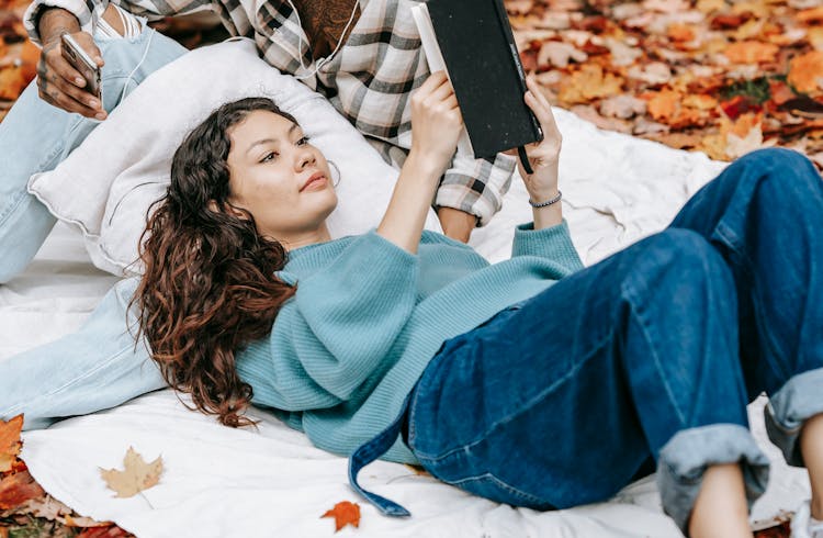 Focused Hispanic Woman Reading Book In Nature