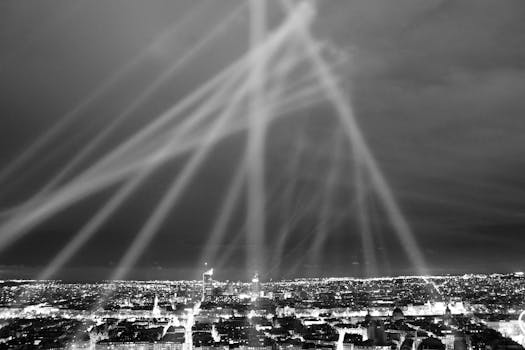 Dramatic nighttime cityscape in grayscale with striking light beams.
