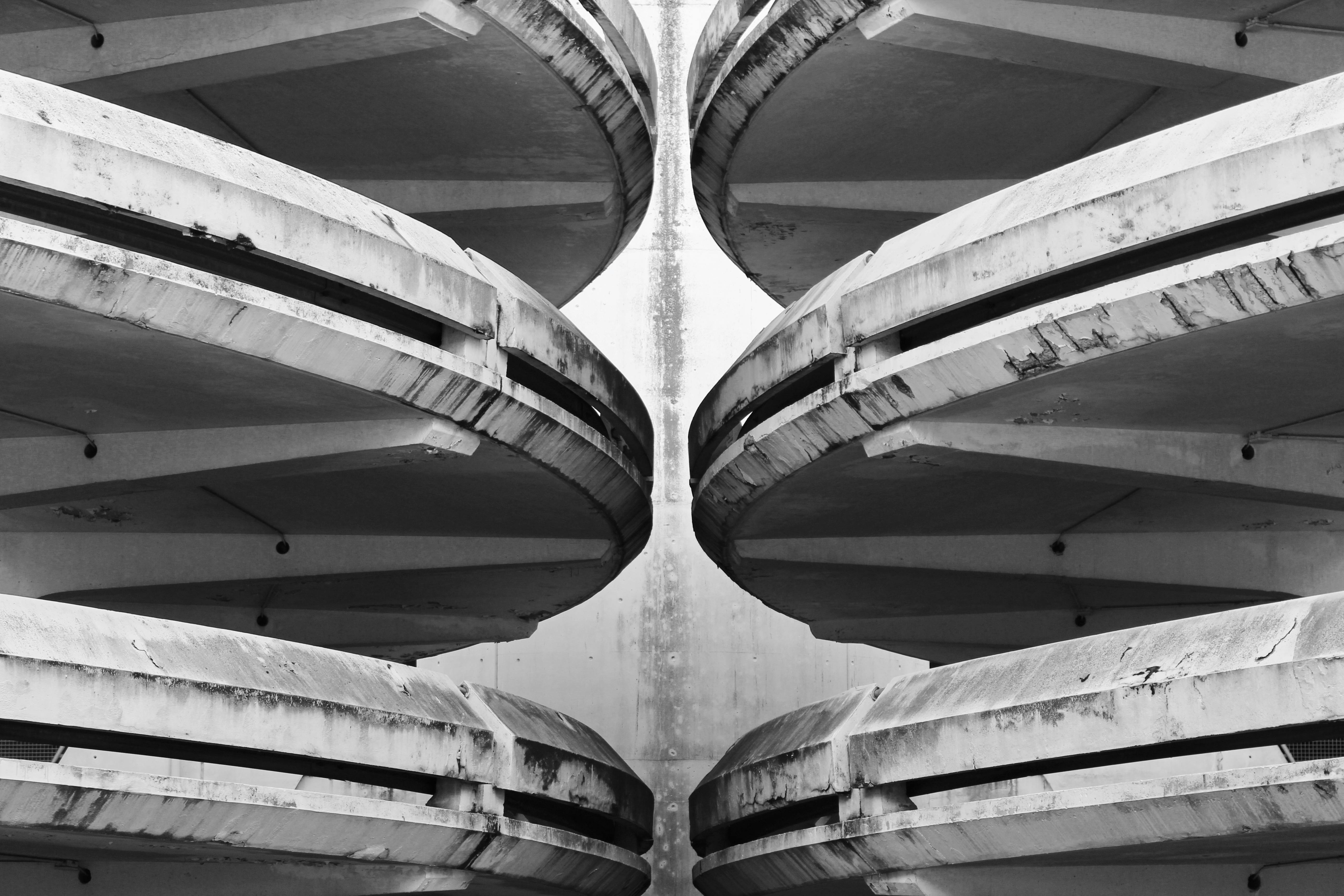 Black and white photo of a symmetrical concrete parking structure with prominent ramps.