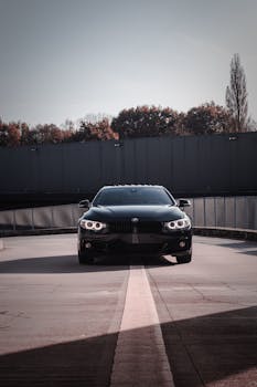 Elegant black car parked on a sunlit urban street in Munich, Germany.