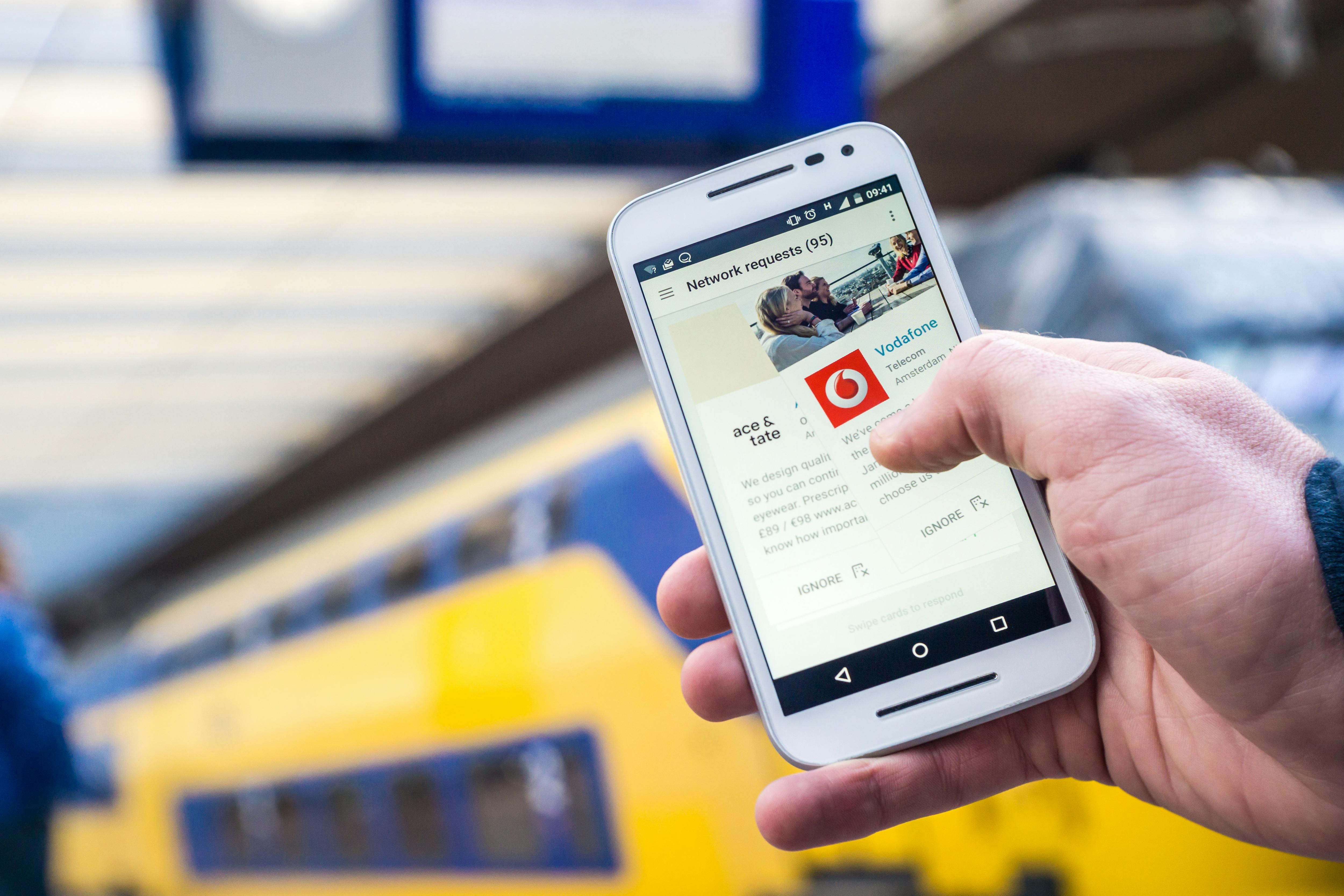 Free Close-up of a person using a smartphone with a train in the background, outdoors. Stock Photo