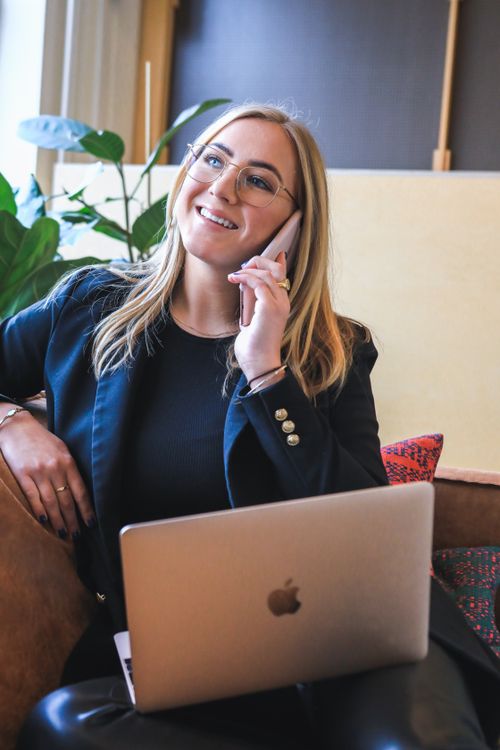 Free Confident young professional woman working remotely on phone call, utilizing laptop in modern setting. Stock Photo