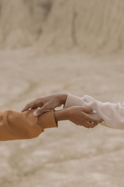 Close-up of two hands gently holding each other against a natural background.