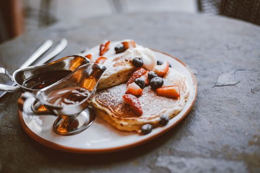 Fluffy pancakes topped with fresh berries and served with syrup, perfect for a delicious breakfast.