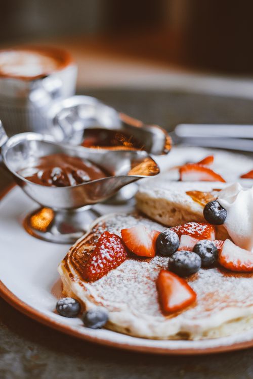 Free Mouthwatering pancakes topped with juicy strawberries and blueberries, served with syrup. Stock Photo