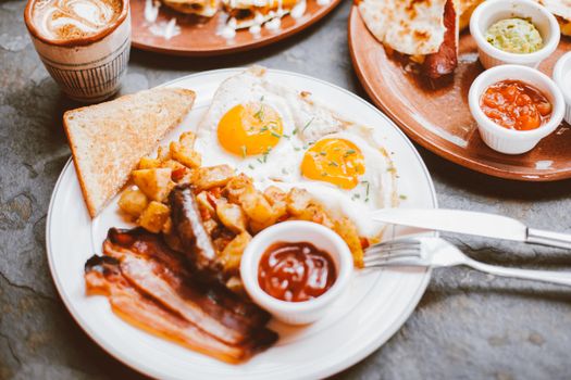 Delicious breakfast with sunny side up eggs, bacon, toast, and coffee.