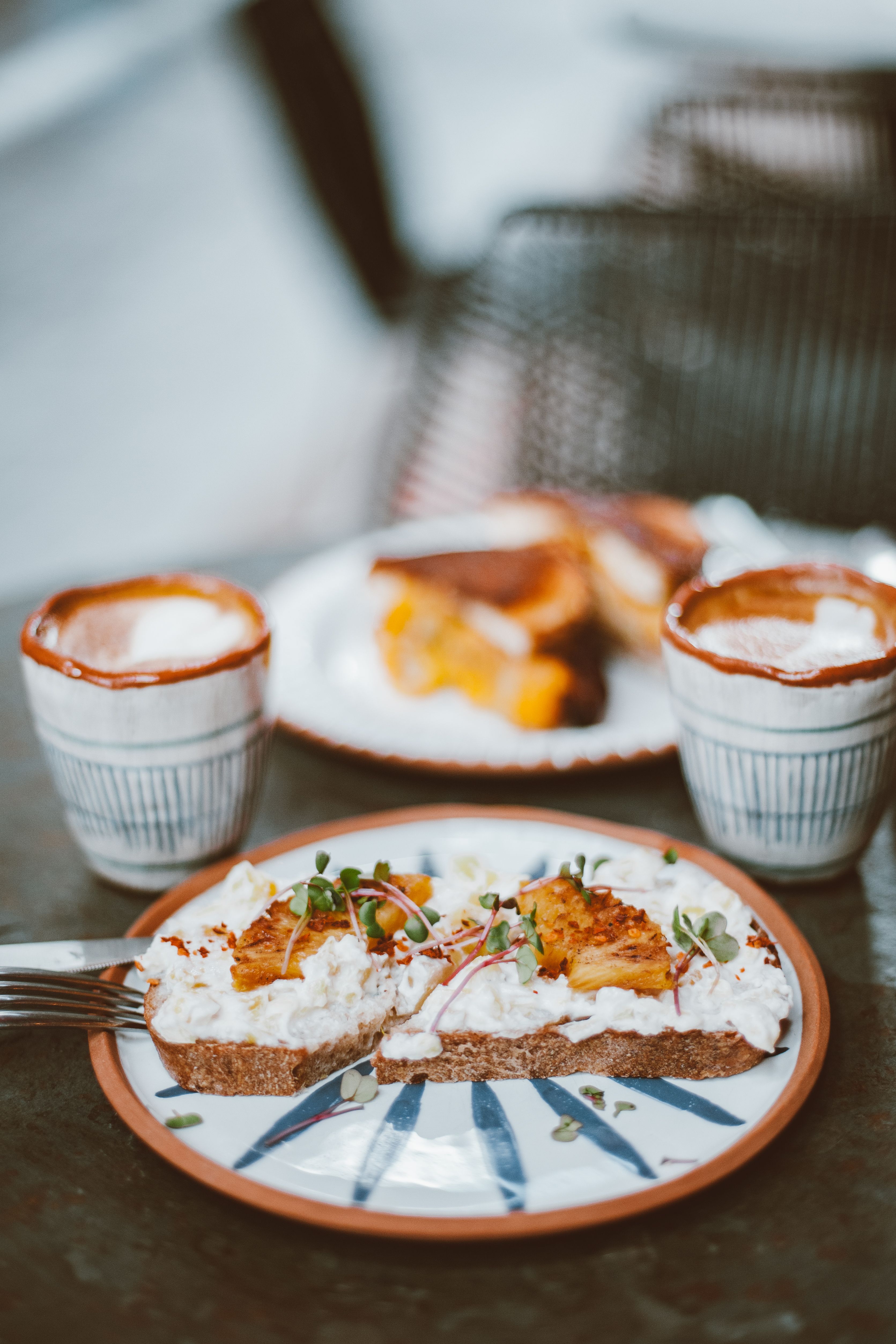 Rustic breakfast scene with artisanal bread, toppings, and two coffee cups.