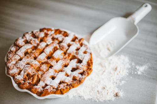 A Pie and Scooper and Spilled Flour on a Flat Surface