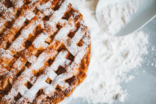 Free Close-up of a lattice-top apple pie dusted with powdered sugar, perfect for indulgence. Stock Photo