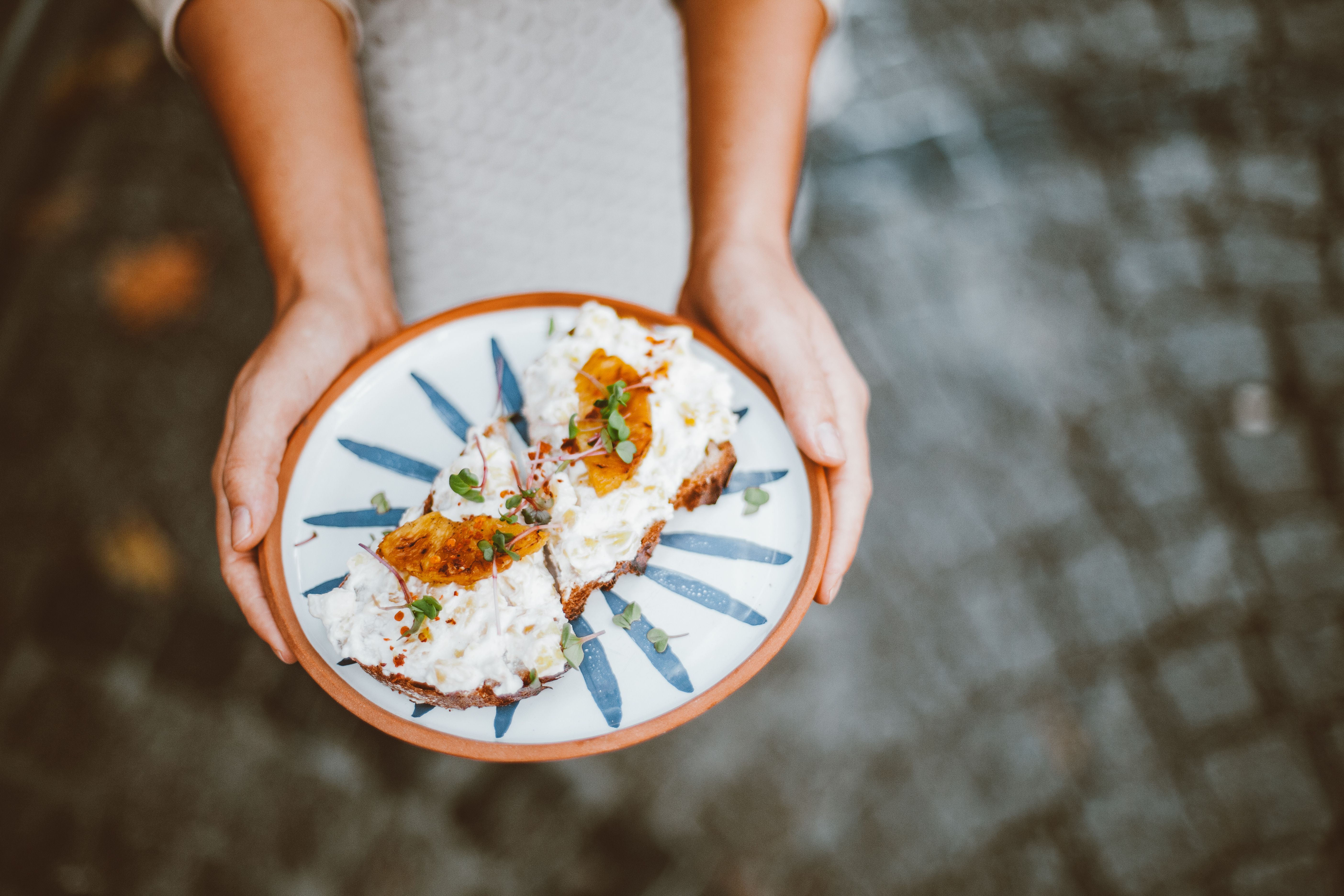 Close-up of a delicious open-faced sandwich with fresh toppings held outdoors.