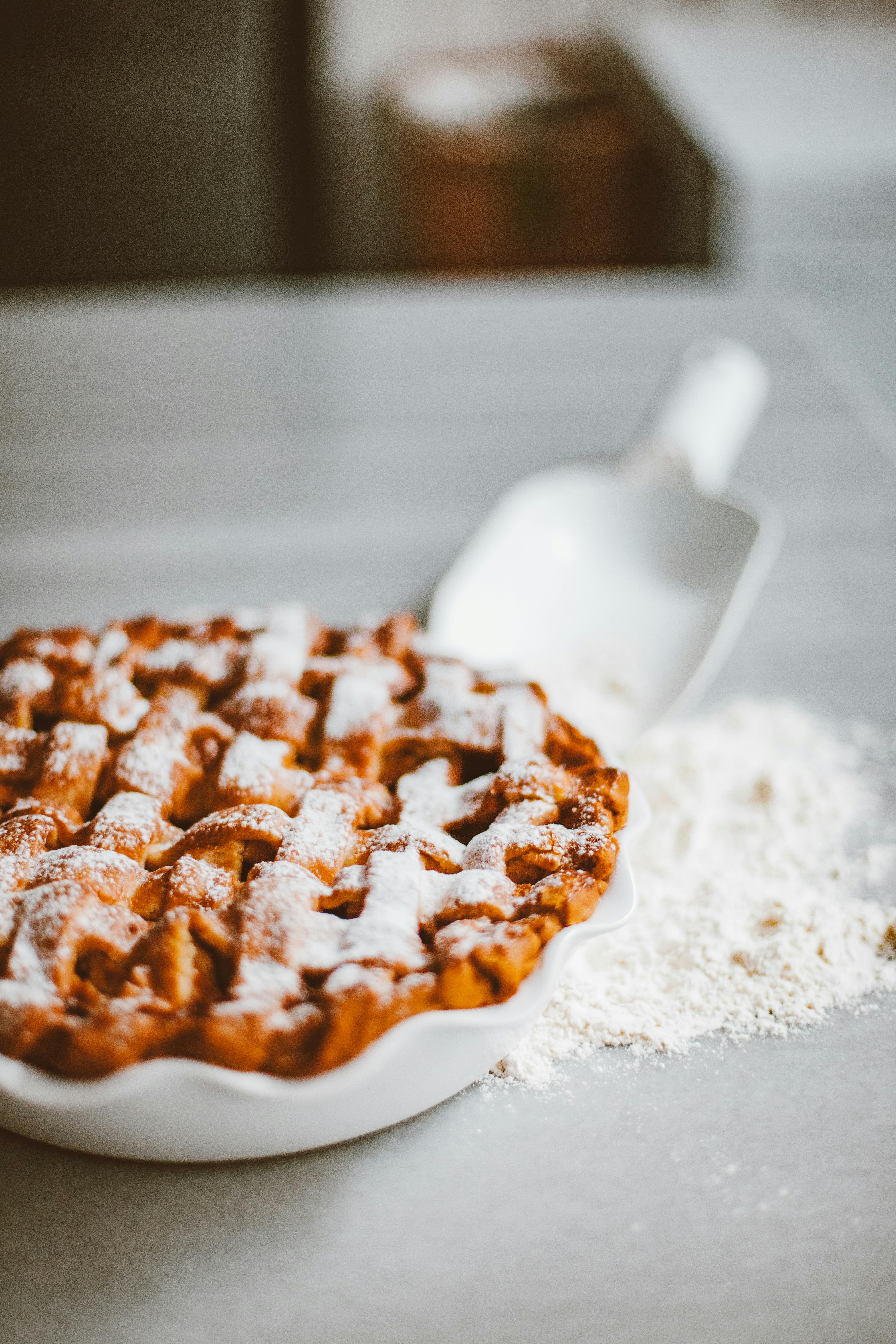 a pie in a plate and spilled flour on a flat surface