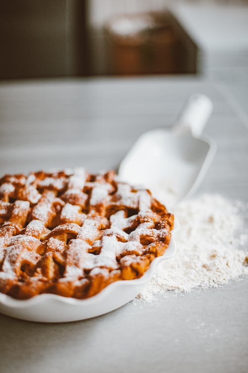 A Pie in a Plate and Spilled Flour on a Flat Surface