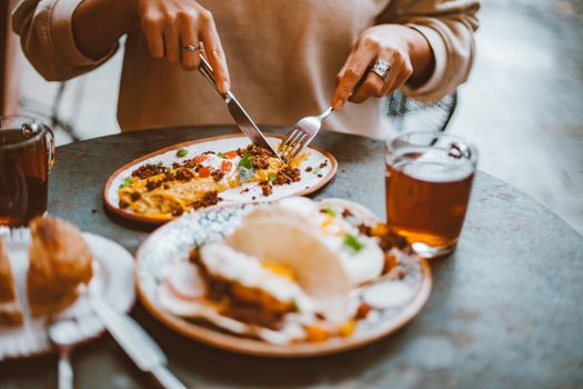 A cozy brunch setting featuring plates of food with a person slicing their meal, creating a warm atmosphere.