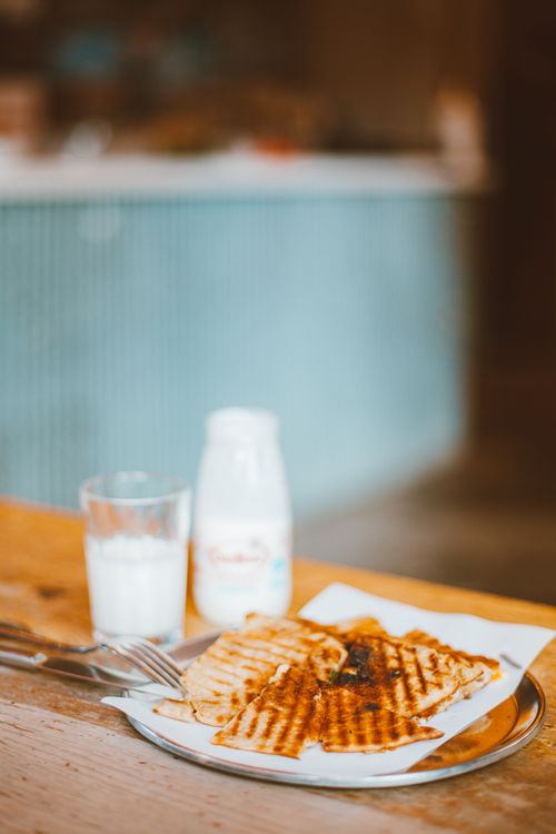 Free Close-up of a grilled sandwich with a glass of milk on a wooden table. Stock Photo