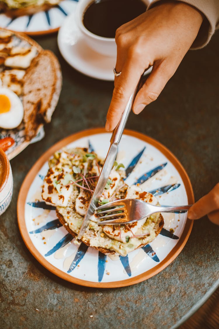 Close-up of Woman Cutting Food On A Table