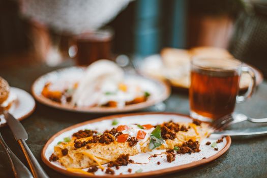 A close-up of a delicious breakfast omelette served with tea on a vibrant plate.