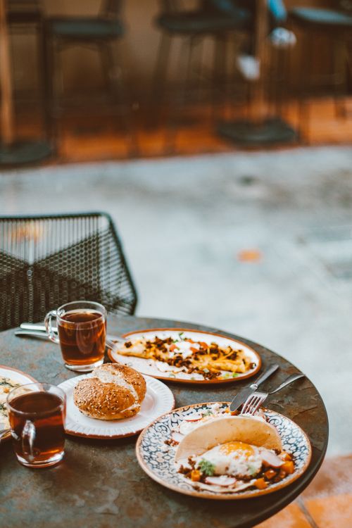 Free Warm breakfast setting outdoors featuring bread, tea, and elegant plates on a round table. Stock Photo